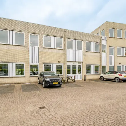 Exterior view of an office building at Regulierenring 2, Bunnik, featuring a parking area with several cars.