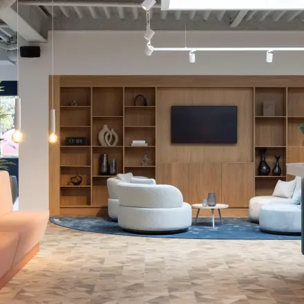 Modern office lounge at Essebaan 63 in Capelle aan den IJssel, featuring stylish seating and a large wall-mounted screen, suitable for office space rental.