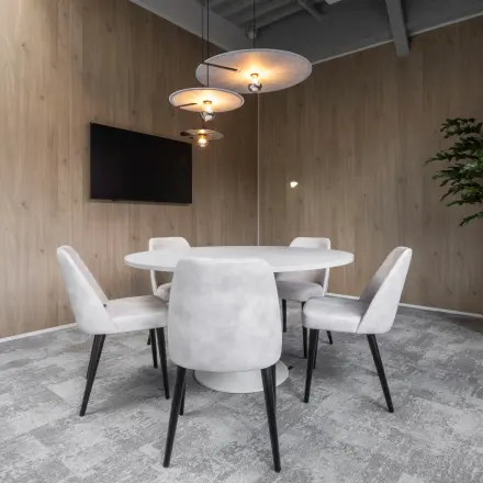 Stylish office interior at Essebaan 63, Capelle aan den IJssel, featuring a round table, chairs, and a wall-mounted TV, ideal for workspace rental.