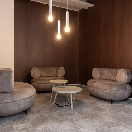 Furnished office lounge area with modern brown sofas and round tables, ideal for office space rental at Essebaan 63, Capelle aan den IJssel.