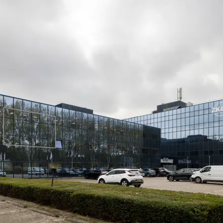 Exterior view of office building located at Essebaan 63, Capelle aan den IJssel, showcasing glass facades and a parking area, ideal for office space rental.