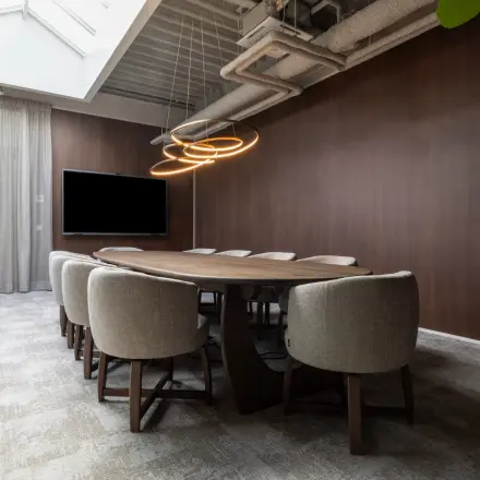 Modern conference room available for office space rental at Essebaan 63, Capelle aan den IJssel, featuring a wooden table, cushioned chairs, and ambient lighting.