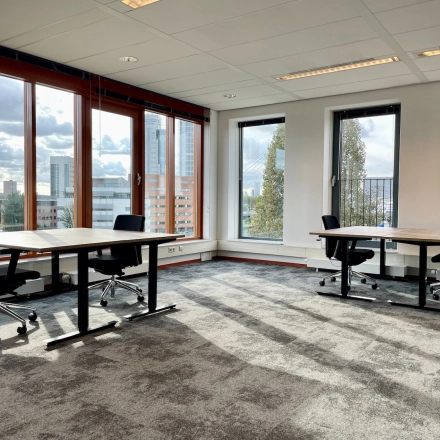 Bright and airy office interior at Fascinatio Boulevard 562 in Capelle aan den IJssel, featuring large windows, two modern desks with chairs, available for office space rental.