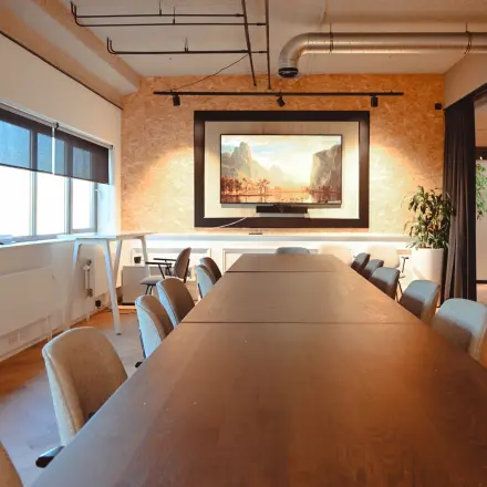 Spacious meeting room with a long wooden table, chairs, and a large framed artwork on the wall, available for office space rental at Rivium Quadrant 75.