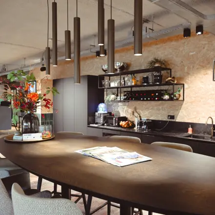 Modern office space at Rivium Quadrant 75, featuring a stylish kitchenette with a large wooden table and contemporary seating, ideal for office space rental.