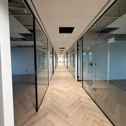Interior view of unfurnished office space at Vlierbaan 20 in Capelle aan den IJssel, with glass-walled rooms and a wooden floor, ideal for office space rental.