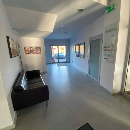 A bright office entrance area at Marcika 27 in Cracow Łagiewniki Borek Fałęcki, featuring a modern black sofa and artwork on the walls. Ideal for office space rental.