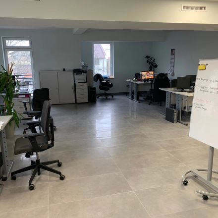 Furnished office space rental at Jastrzębia 24 in Cracow Podgorze Duchackie, featuring desks, chairs, and a whiteboard, available for rent. Bright workspaces with windows and indoor plants.