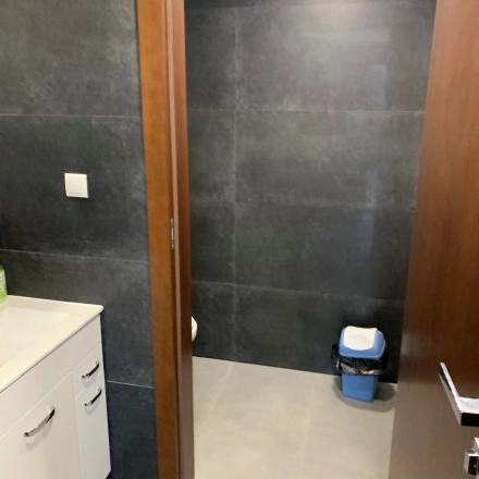Modern office restroom with dark tiles, sink cabinet, and waste bin at Jastrzębia 24 in Cracow Podgorze Duchackie, ideal for office space rental needs.