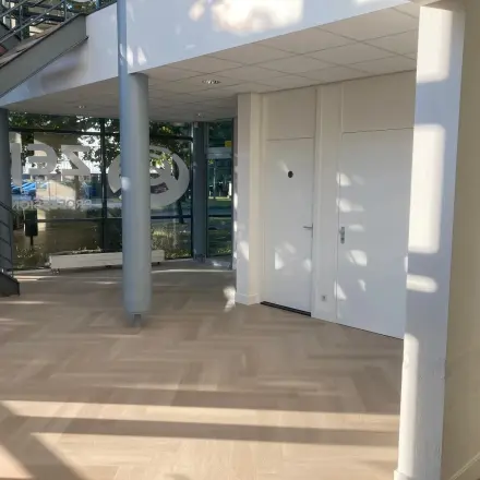 Interior of an office space at Delftechpark 17-19, Delft, showcasing a well-lit area with parquet flooring and a modern staircase, ideal for office space rental.