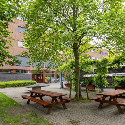 Exterior view of an office building at Delftechpark 9, Delft, featuring a green outdoor seating area ideal for office space rental breaks.