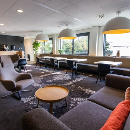 Bright and inviting office space for rent at Marshalllaan 2, Delft, featuring modern furniture with comfortable seating and ample natural light from large windows.