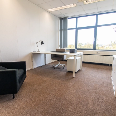 Bright office space to rent at Marshalllaan 2, Delft, featuring a desk and chair with large windows providing natural light. Ideal for office space rental.