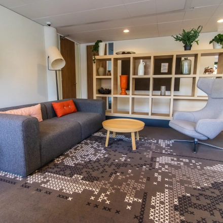 Cozy office space for rent at Marshalllaan 2, Delft, featuring a furnished lounge with a sofa, armchair, and decorative shelving. Ideal for office space rental.