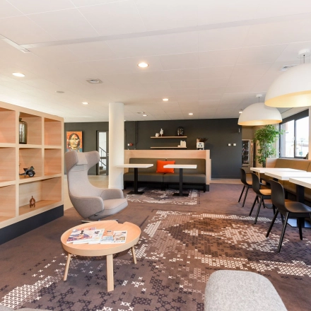 Bright, furnished office space with modern seating and large windows at Marshalllaan 2, Delft. Ideal for office space rental with flexible work areas.