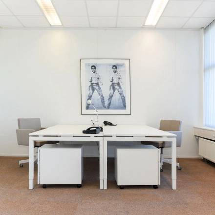 Bright office space for rent at Marshalllaan 2, Delft, featuring two white desks and chairs with a motivational poster on the wall.