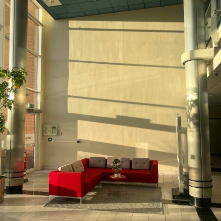 Bright office lobby at Olof Palmestraat 10, Delft with modern red seating and large windows, ideal for rent office space.