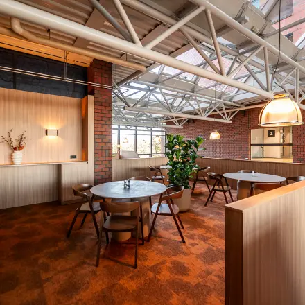 Furnished office space with round tables and chairs under large skylights at Hambakenwetering 5, Den Bosch, ideal for office space rental.