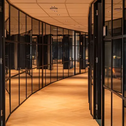 Curved glass-walled office corridor at Reitschweg 1, Den Bosch, ideal for office space rental.