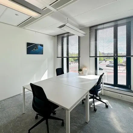 Bright office space for rent at Willemsplein 2, Den Bosch, featuring large windows, modern lighting, and a table with chairs, ideal for meetings.