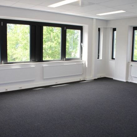 Unfurnished office space with large windows and carpeted floor, ideal for those looking to rent office space in Deventer.