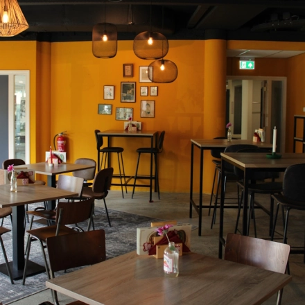 Lively office space for rent at Keulenstraat 10, Deventer, featuring modern furnishings with wooden tables and chairs, warm lighting, and wall decor. Ideal for office space rental.