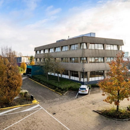 Exterior view of an office building at Staverenstraat 15-17 in Deventer with surrounding autumn trees. Ideal for office space rental.