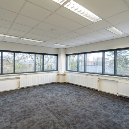 Bright office space available for rent at Staverenstraat 15-17, Deventer, featuring large windows and carpeted floors.