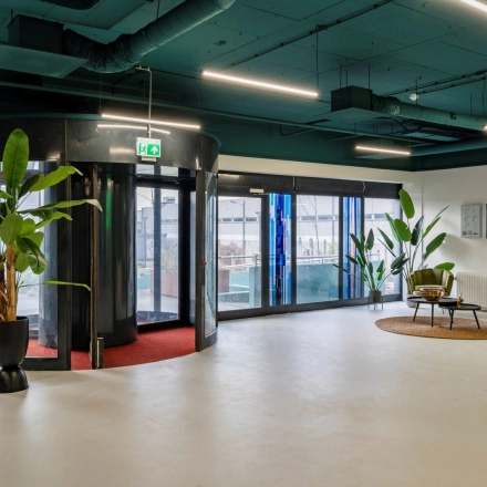 Spacious office entrance at Staverenstraat 15-17, Deventer, featuring modern design with potted plants and natural light. Ideal for those seeking office space rental.