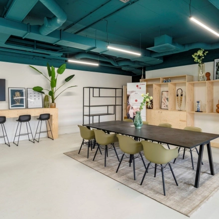 Spacious office to rent at Staverenstraat 15-17 in Deventer featuring a stylish meeting table, bar stools, and decorative elements for an inviting office space rental experience.