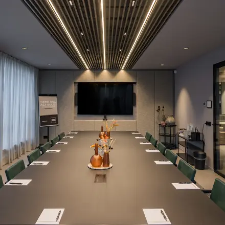 A modern conference room at Diemerhof 42, Diemen, available for office space rental. The room features a large table, chairs, and a flat-screen TV, ideal for meetings and presentations.