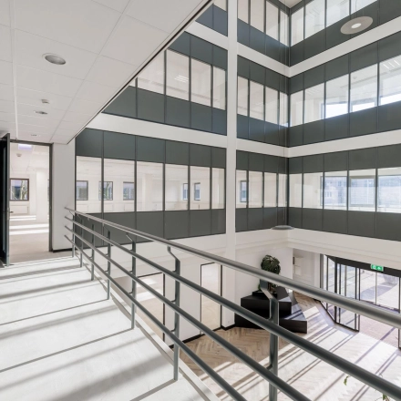 Bright and spacious interior hall with large windows and a view of a multi-story office structure, ideal for office space rental at Wisselwerking 40-48, Diemen.