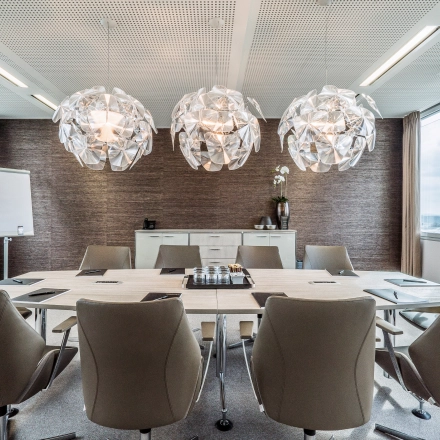 Stylish conference room with modern lighting and large meeting table, located in Dreischeibenhaus 1, perfect for office space rental in Düsseldorf Old Town.
