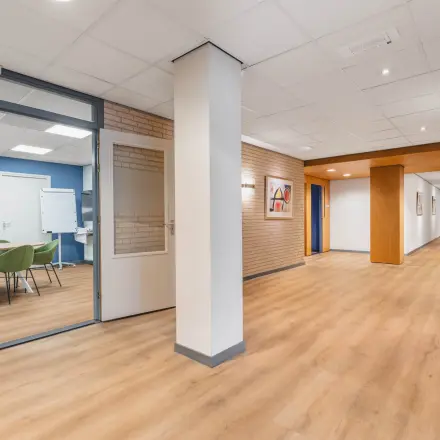 Spacious office hallway at Kanaaldijk-Zuid 19, Eindhoven Center, leading to various meeting rooms suitable for office space rental.