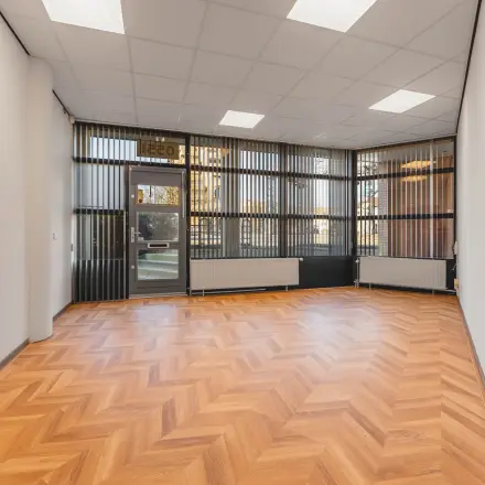 Bright, unfurnished office space with herringbone wood flooring and large windows at Kanaaldijk-Zuid 19, ideal for rent in Eindhoven Center.