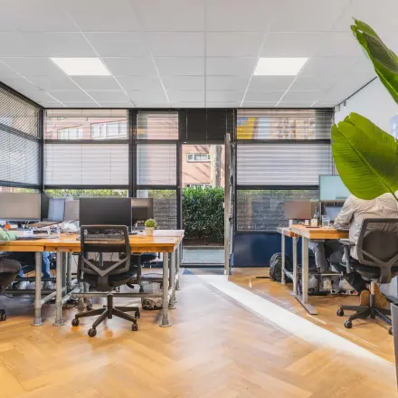 Modern office space at Kanaaldijk-Zuid 19, Eindhoven Center with desks, chairs, and people working on computers.