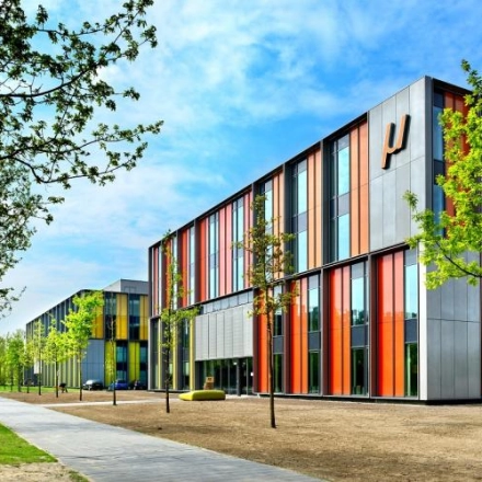 Exterior of Eindhoven High Tech Campus at High Tech Campus 10, showcasing modern, colorful architecture surrounded by trees and a clear sky, ideal location for office space rental in an innovative environment.