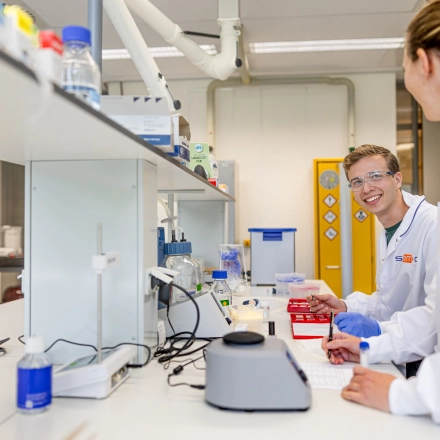 A modern laboratory space at High Tech Campus 9 in Eindhoven, featuring researchers engaged in scientific activities, equipped with lab apparatus and safety gear, suitable for innovative projects.