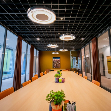Spacious conference room at High Tech Campus 9, Eindhoven with modern lighting and a large table, ideal for office space rental. Surrounded by glass walls, enhancing communication and collaboration.