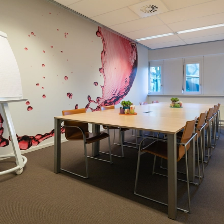 Modern conference room with a large wooden table, stylish chairs, and a flipchart, ideal for office space rental at TU campus, De Zaale 11, Eindhoven High Tech Campus.