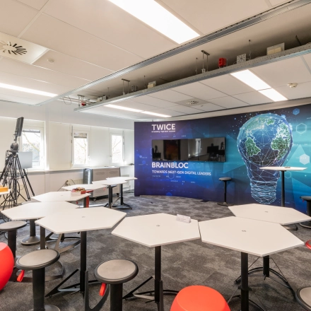 Modern office space at TU campus, De Zaale 11, Eindhoven High Tech Campus, featuring innovative workspaces with unique hexagonal desks and a digital-themed wall, ideal for office space rental.