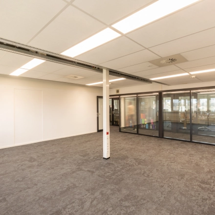 Interior view of an unfurnished office space with carpet flooring and ceiling lights at TU campus, De Zaale 11, Eindhoven High Tech Campus, suitable for office space rental.
