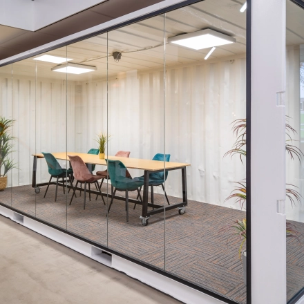 Modern conference room in Eindhoven North, featuring a sleek glass-walled design and colorful chairs, available for office space rental at Tarasconweg 2.