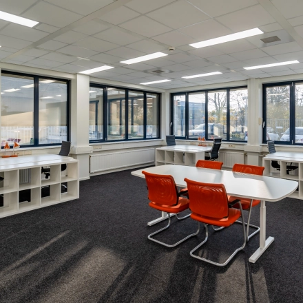 Bright office space with rows of white desks and orange chairs at Tarasconweg 2, Eindhoven North. Large windows provide ample natural light, ideal for office space rental.