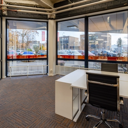 Bright, furnished office space at Tarasconweg 2, Eindhoven North, featuring large windows and a modern desk setup, ideal for your next office space rental.