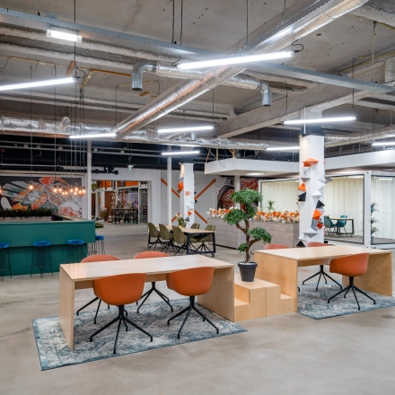 Modern open workspace at Tarasconweg 2, Eindhoven North, featuring contemporary desks, vibrant chairs, and creative lighting, ideal for office space rental.