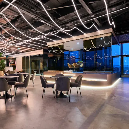 Modern office space with sleek lighting, furnished with round tables and chairs, creating a dynamic environment for renters at Achtseweg Zuid 159R, Eindhoven Strijp-S.