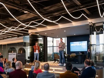 A modern, furnished office space in Eindhoven Strijp-S with people attending a presentation, ideal for office space rental.