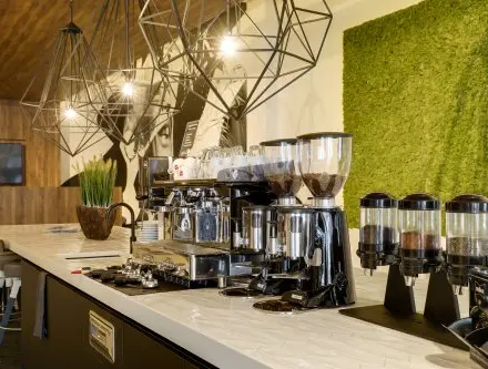 Modern office lounge area at Frederiklaan 10E, Eindhoven Strijp-S, featuring coffee machines and stylish lighting fixtures, ideal for office space rental.