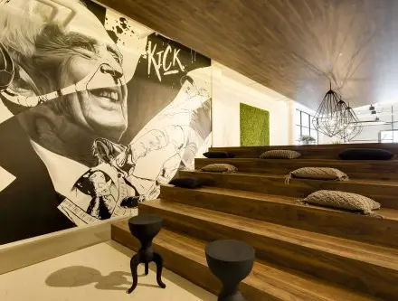 Stylish office space at Frederiklaan 10E, Eindhoven Strijp-S with tiered wooden seating, modern decor, and wall art. Ideal for creative workspace and office space rental.